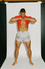 Athletic male model wearing Y,IWO x Ace Hotel grey bodybuilding shorts with a 2.25-inch inseam and blue vintage gym graphics, lifting his red T-shirt to reveal his ripped abs against a white studio backdrop.