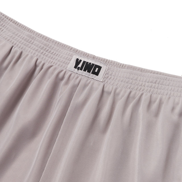 Close-up of the Y,IWO x Ace Hotel grey microfiber quad shorts showing the elastic gathered waistband, woven Y,IWO logo label, and lightweight athletic fabric.