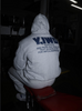 Person wearing a hoodie with text on the back, sitting in a dark room.